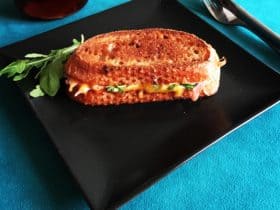 Toast med cheddar, skinke, syltede rødløg, dijonnaise, rocula og soltørrede tomater